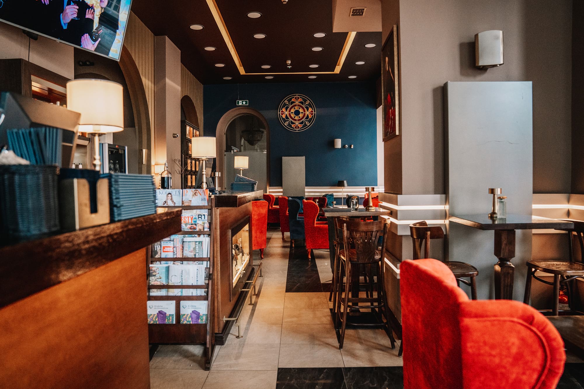 Stylowy bar z czerwonymi fotelami, lampami i niebieską ścianą w tle