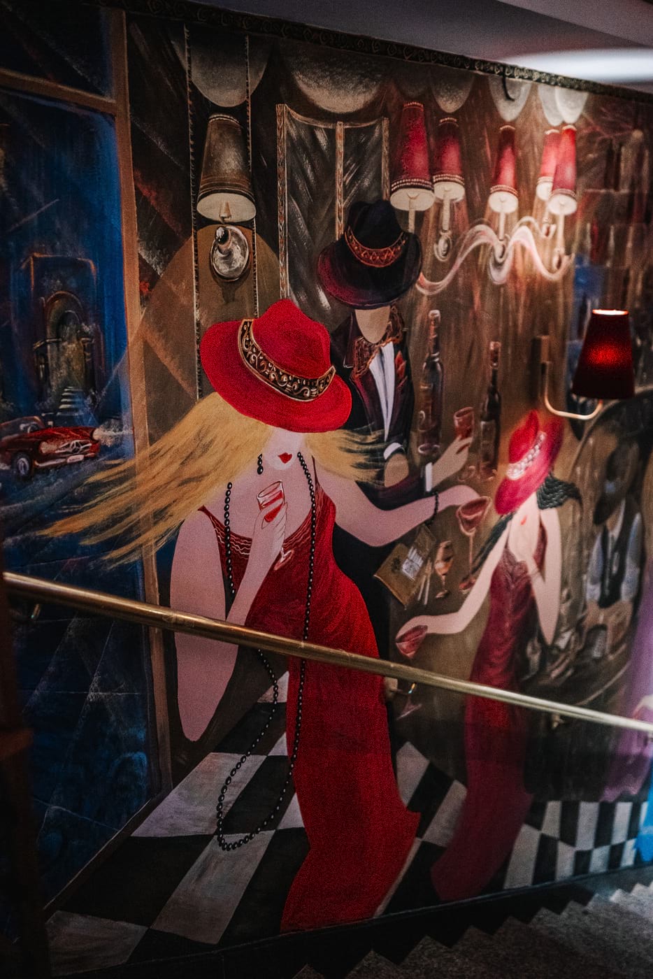 Mural z elegancką kobietą w czerwonym kapeluszu i sukni, z kieliszkiem w dłoni, w stylowym wnętrzu