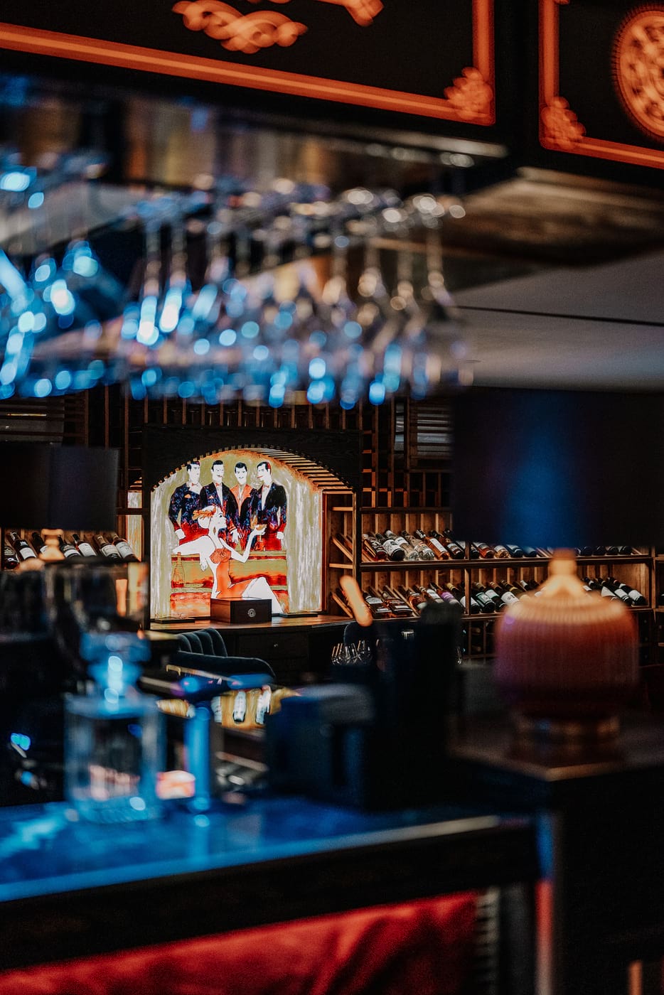 Elegancki bar z półkami na wino i kolorowym obrazem w centrum, widziany przez rozmyte kieliszki