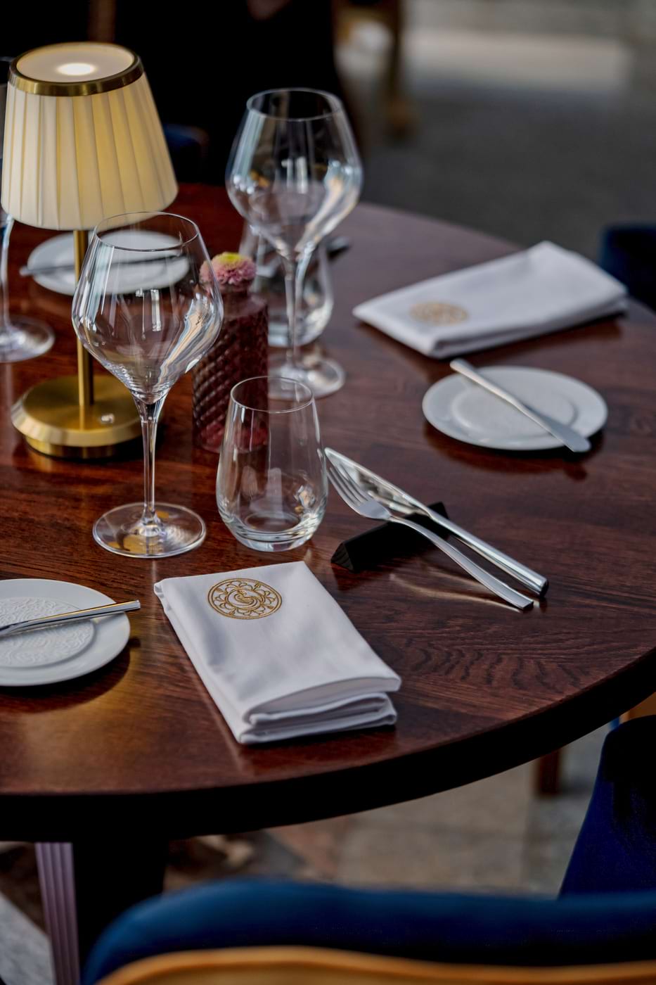 Elegancko nakryty stół w restauracji z kieliszkami, sztućcami, serwetkami i lampką stołową